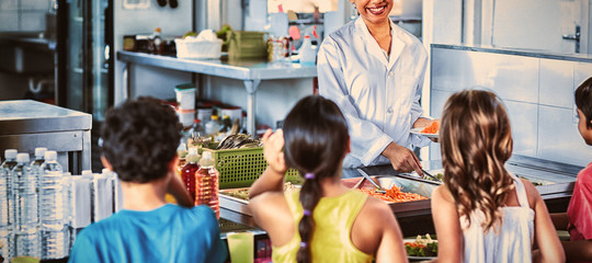 Woman serving food to schoolchildren