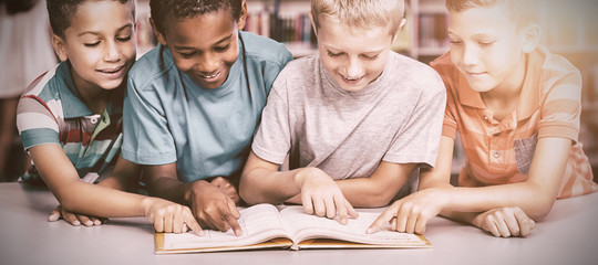 School kids reading book together in library