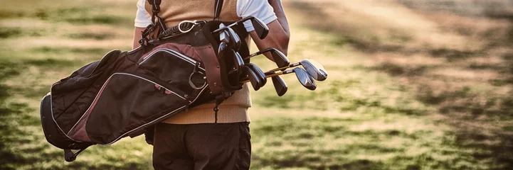 Abwaschbare Fototapete Golf Mann trägt Golftasche, während er auf dem Feld steht