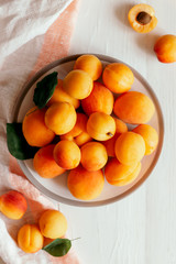 Delicious ripe organic apricots on a white plate and wooden table.