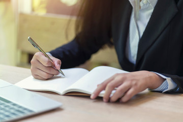 Businesswoman hand writing checklist on notebook, planning concept.