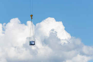 Fototapeta premium Hook crane with cargo against the sky with white patches