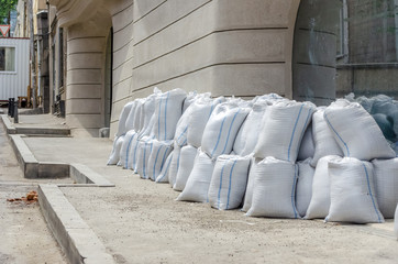 Lots of bags of cement or sand near the wall for building or laying tiles close up