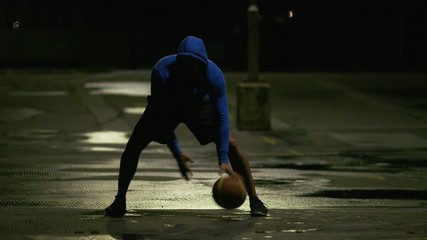 Professional basketball player dribbling the ball with skill under a street light at night - Powered by Adobe