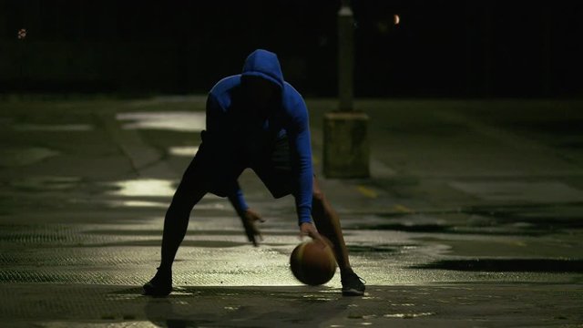 Professional basketball player dribbling the ball with skill under a street light at night