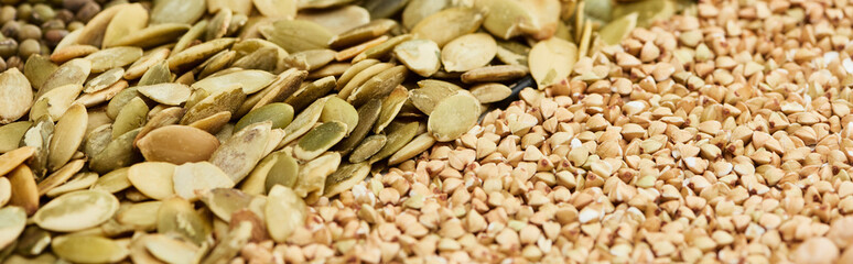 panoramic shot of raw buckwheat and pumpkin seeds