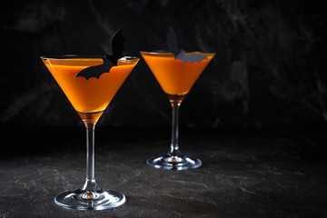 Orange pumpkin  martini Halloween drink for party over black background with copy space