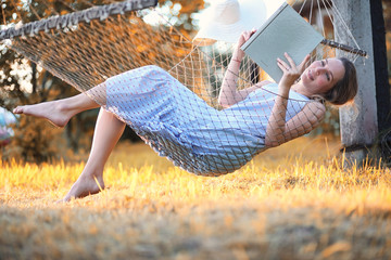 Beautiful girl in hammock reading a book