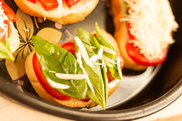 making sandwiches with tomato and basil on a baking sheet for the oven
