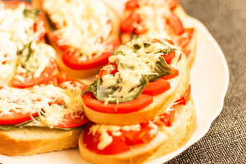 making sandwiches with tomato and basil on a baking sheet for the oven