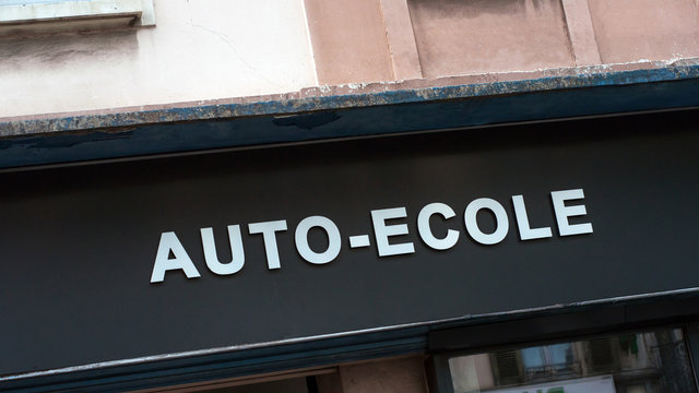 Closeup of driving school signage in french ( auto ecole) on building facade