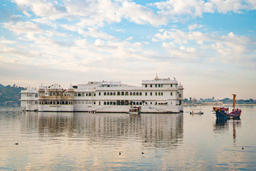 Naklejka premium Morning view of lake Pichola and Taj Lake Palace with boats from Ambrai Ghat in Udaipur, Rajasthan, India
