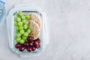 Meal prep containers with grapes and crispbread. Breakfast fruits in lunch box. Top view, copy space.