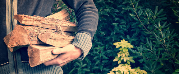 Man carrying firewood logs in autumn, wood chop for winter, header with copy space