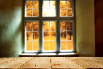 Wooden desk of free space and autumn window background 