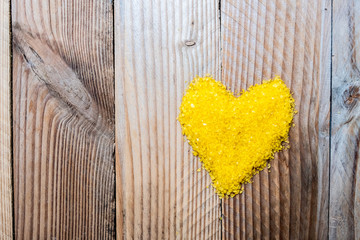 Coeur jaune en grains de sel sur fond bois vintage