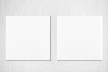 Two empty white square flyer or business card mockups with soft shadows on neutral light grey textured background. Flat lay, top view