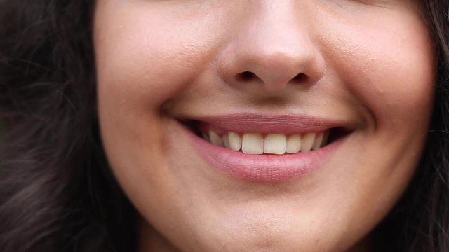 Happy smiling lips in close-up. Unrecognizable woman with pink lips smiling in closeup.