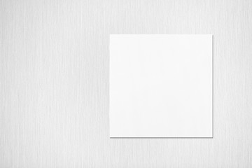 Empty white square flyer or business card mockup with soft shadows on neutral light grey textured background. Flat lay, top view