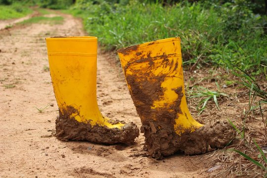Farmers' yellow waterproof boots are mud on rural roads