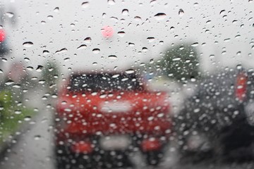 Water droplets on the windshield are on the road while heavy rain shoots blur images
