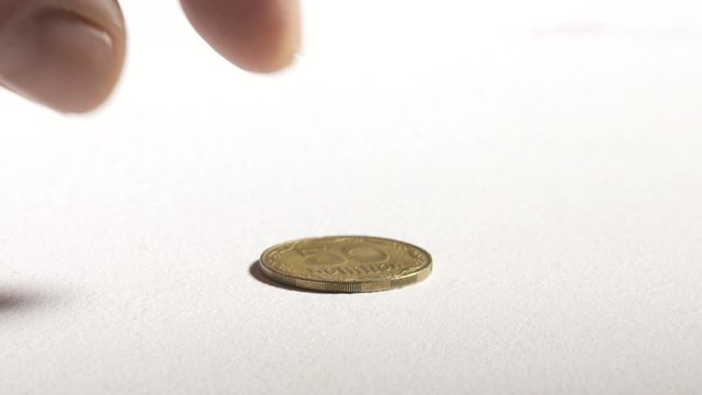Hand taking 50 Ukrainian kopiyok coin from desk showing reverse side. 50 kopiyok equivalent to half a hryvnia. Currency of Ukraine.