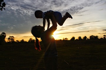 The silhouette of the mother and son on playing joyfully, the golden-yellow sky at sunset, Take a blur