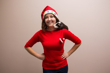 Photo of happy girl and funny guinea pig in santa hat