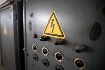 Danger of electrocution yellow sign on gray background. High voltage warning sign. Electric bolt in...