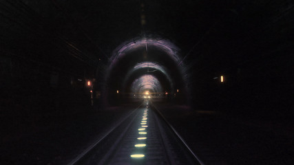 Bright train lights coming towards camera in a dark railway tunnel