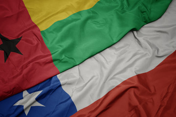 waving colorful flag of chile and national flag of guinea bissau.