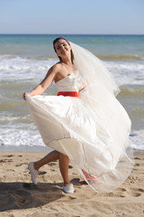 Fototapeta na wymiar Happy bride walking on a sea beach