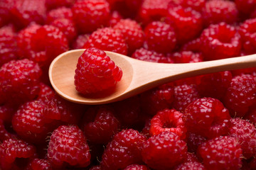 Raspberry berry in a wooden spoon. Ripe red raspberries close-up.