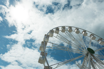 Ferris wheel on the blue cloudy sky. Background concept of happy holidays time.