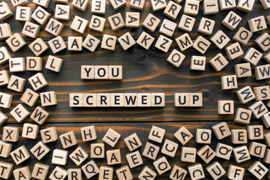 You screwed up - phrase from wooden blocks with letters,  doing something stupid concept, random letters around, white  background