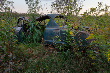 Damaged automobile, lost and forgotten, surrounded by weeds and shrubs in Lackawanna County, Pennsylvania. This antique wreckage was discovered in early 2019 when a small 10 acre area was cut down to 