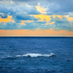 Big wave, colorful sunset over the sea with blue sky and clouds