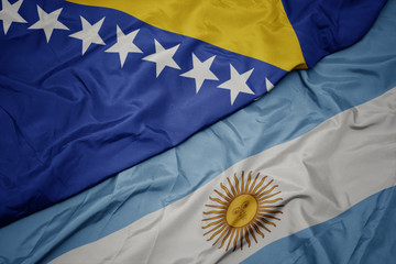 waving colorful flag of argentina and national flag of bosnia and herzegovina.