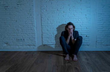 Desperate lonely teenager man suffering from depression sitting alone on floor at home