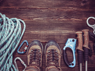 climbing equipment: rope, red helmet, hammer, trekking shoes and other set  on dark wooden background, top view