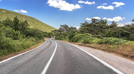 Highway in mountainous terrain. Mountain road on a summer sunny day.