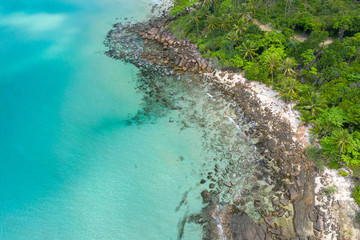 Aerial top view of ocean waves, beach and rocky coastline and beautiful forest. Beautiful nature background.
