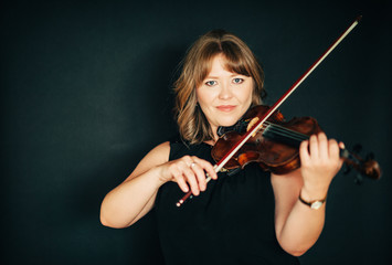 Studio portrait of beautiful woman with violin, black background