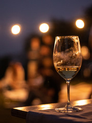 Glass of white wine with fingerprint in the night with people behind in an event with bokeh effect and chillout mood