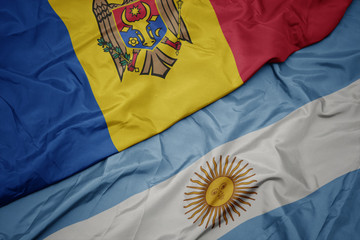 waving colorful flag of argentina and national flag of moldova.