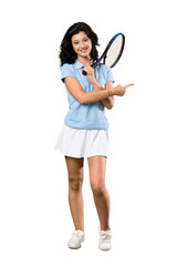 A full-length shot of a Young tennis player woman pointing to the side to present a product over isolated white background