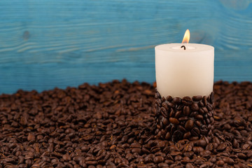Obraz na płótnie Canvas Burning candle among coffee beans