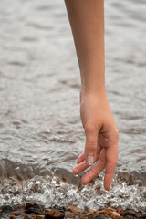 female hand touches small waves on the river