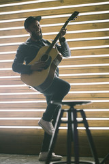 Singer and guitar player singing on a stage with neon lights. He is a rocker and he is wearing...