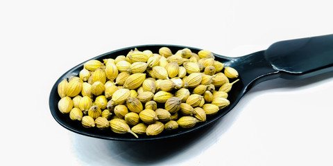 A picture of coriander seed's on black spoon
